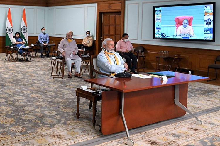 Indian Prime Minister Narendra Modi sits at a desk at the front of the room during a video conference on the COVID emergency